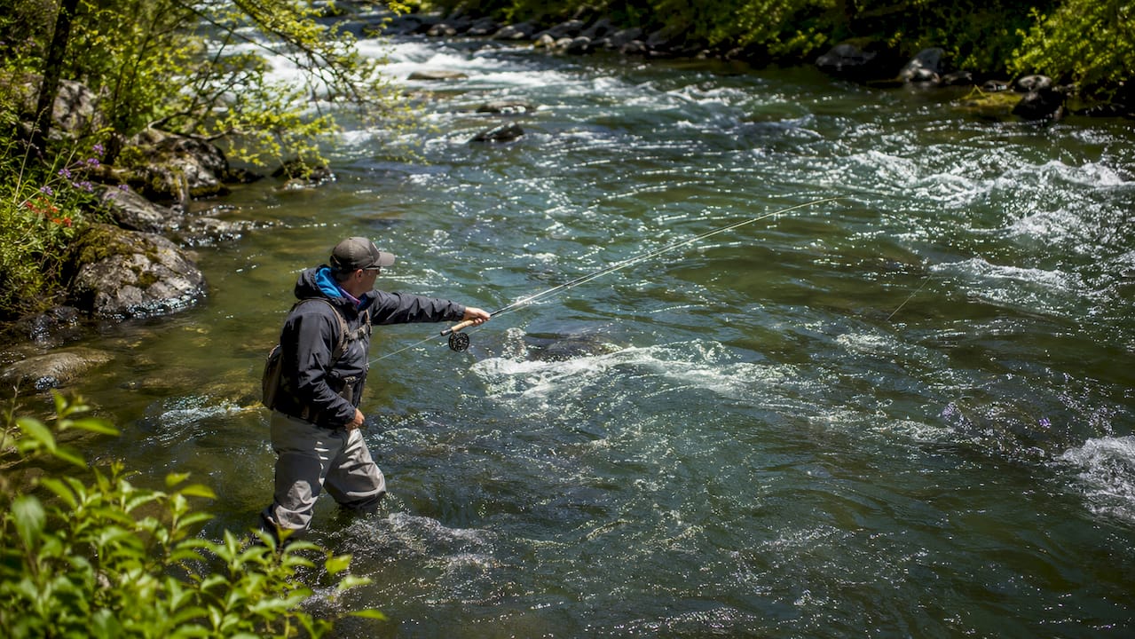 Angler casting spoon lure in PNW river at dawn