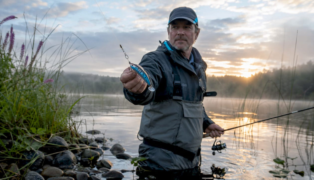 Angler holding Kwikfish lure in river at dawn