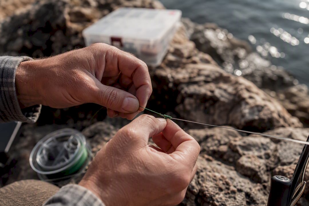 Hands tying double uni knot on fishing line
