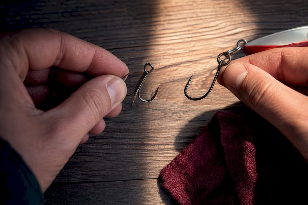 Angler comparing treble and single hooks